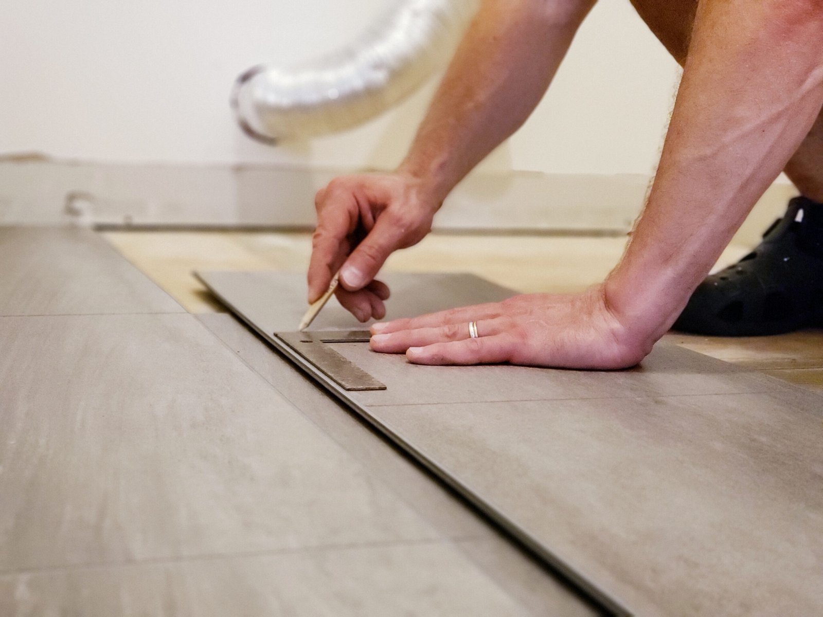 mans hands holding flooring plank and measuring