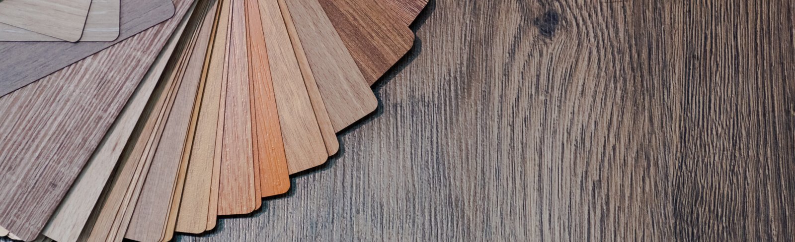 Laminate flooring samples in various wood tones displayed on a hardwood surface